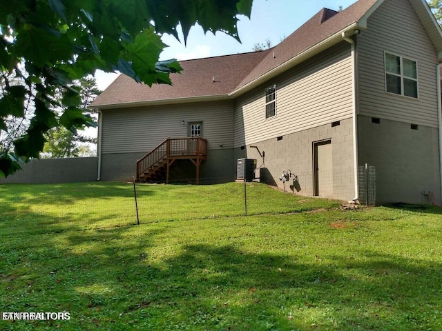 back of property with central AC unit and a yard