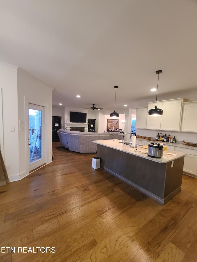 kitchen featuring hardwood / wood-style floors, open floor plan, a center island with sink, and white cabinetry