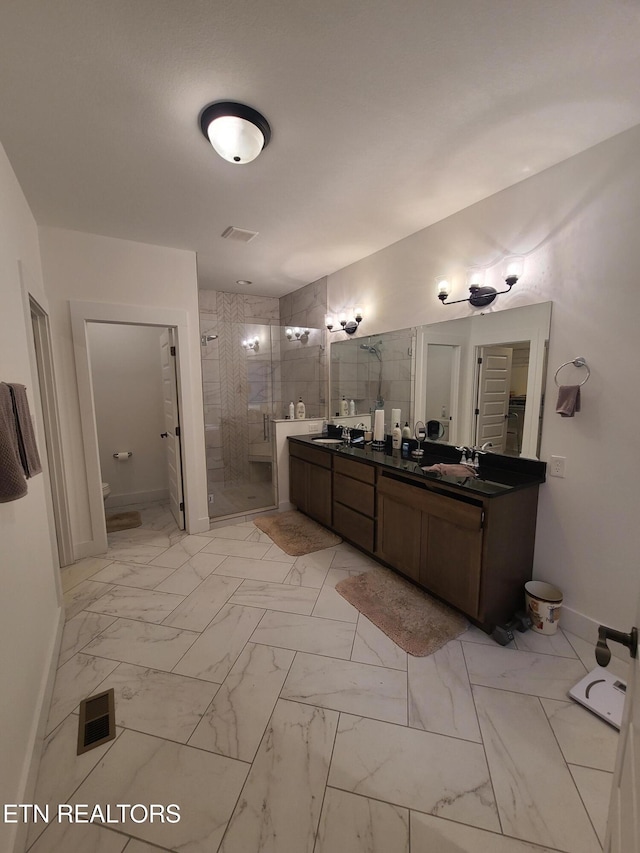 bathroom featuring visible vents, marble finish floor, a shower stall, and double vanity