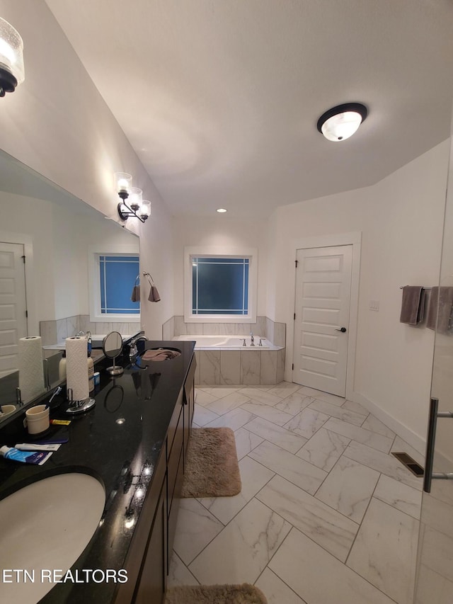 bathroom featuring baseboards, double vanity, a sink, a bath, and marble finish floor