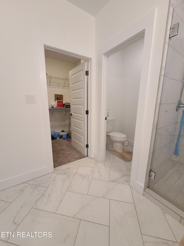 bathroom with baseboards, toilet, marble finish floor, and a shower stall