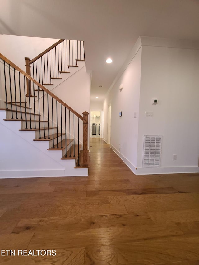 foyer entrance with visible vents, crown molding, baseboards, recessed lighting, and wood finished floors