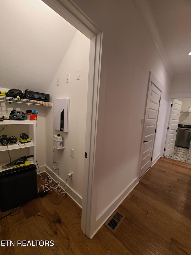 hall with visible vents, baseboards, and wood finished floors