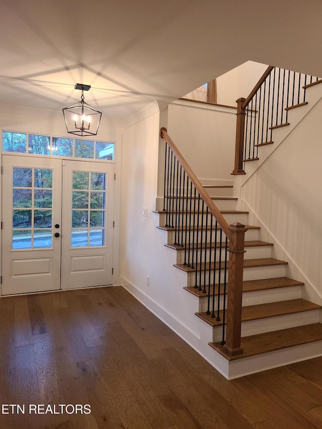 foyer featuring a notable chandelier, hardwood / wood-style flooring, french doors, stairway, and baseboards