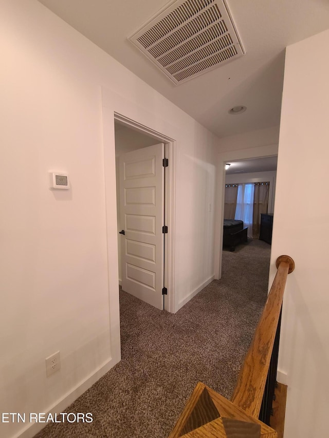 hallway featuring visible vents, carpet floors, and baseboards