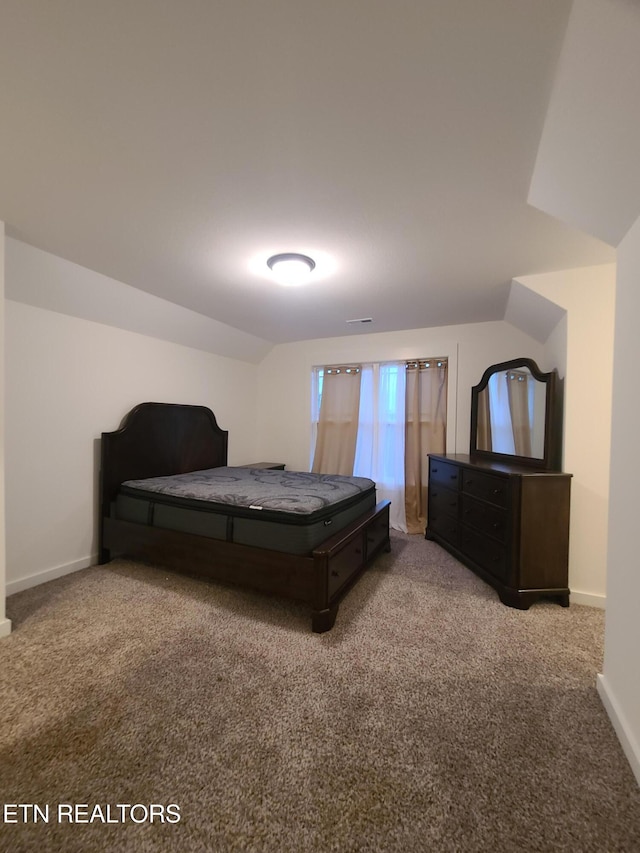 carpeted bedroom featuring lofted ceiling, visible vents, and baseboards