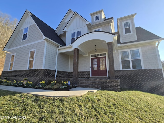 view of front facade featuring french doors, brick siding, board and batten siding, and a front yard