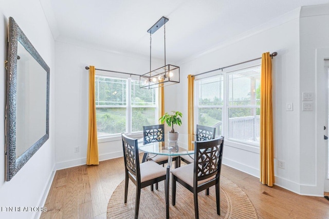 dining space with baseboards, light wood-style floors, an inviting chandelier, and crown molding