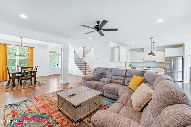 living area with stairway, crown molding, ceiling fan with notable chandelier, and recessed lighting