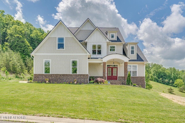 craftsman inspired home featuring board and batten siding, brick siding, french doors, and a front lawn