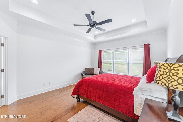 bedroom with wood finished floors, baseboards, a raised ceiling, ceiling fan, and recessed lighting