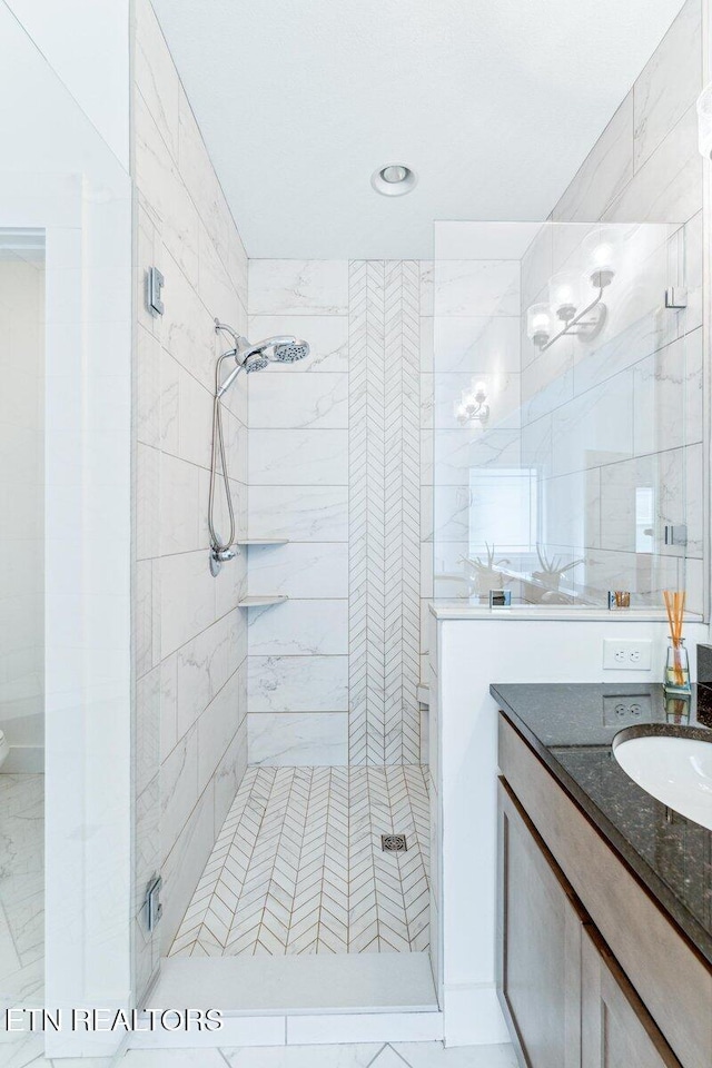 full bathroom with a stall shower, marble finish floor, tile walls, and vanity