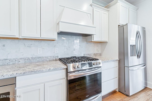 kitchen featuring custom exhaust hood, white cabinets, appliances with stainless steel finishes, and light stone countertops