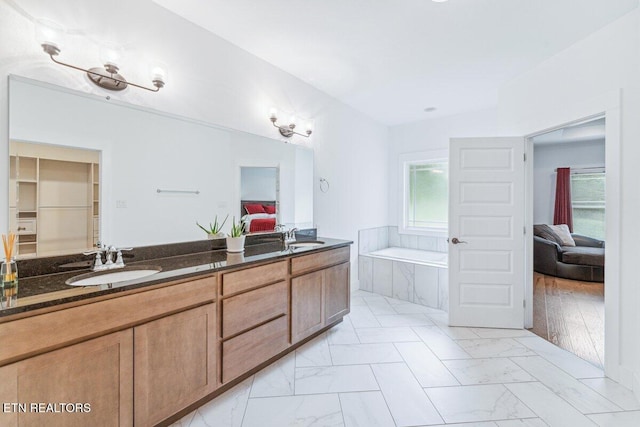 ensuite bathroom featuring a sink, marble finish floor, ensuite bath, double vanity, and a garden tub