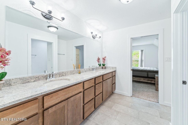 full bathroom with a sink, double vanity, connected bathroom, and baseboards