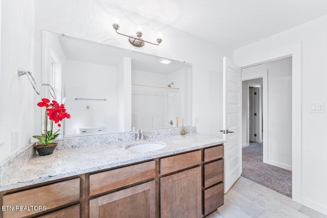 full bathroom featuring walk in shower, baseboards, and vanity
