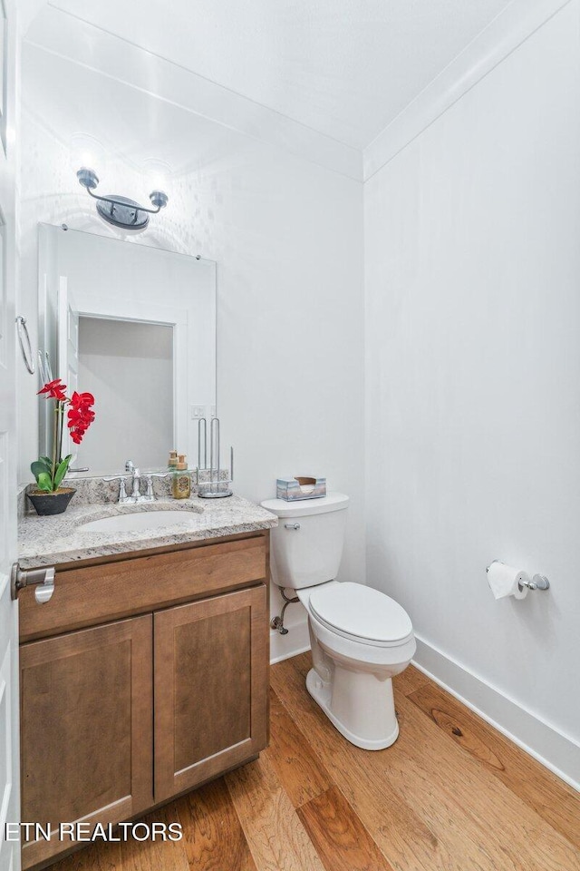bathroom with vanity, toilet, baseboards, and wood finished floors