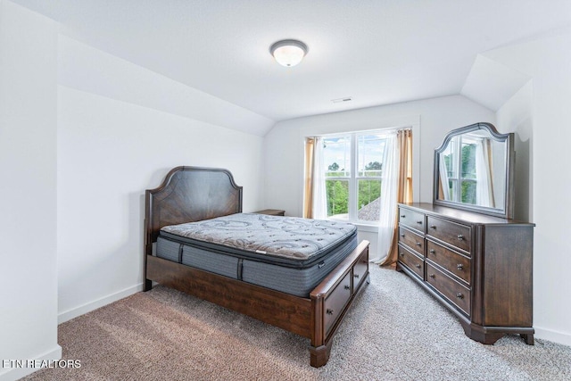 bedroom with light colored carpet, vaulted ceiling, and baseboards