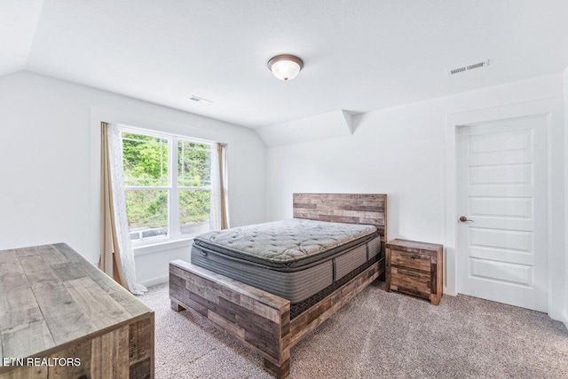 carpeted bedroom with visible vents and vaulted ceiling
