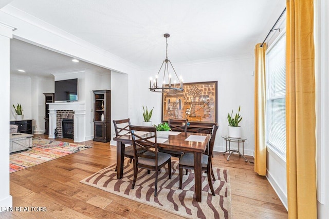 dining space with a wealth of natural light, a notable chandelier, light wood finished floors, and crown molding