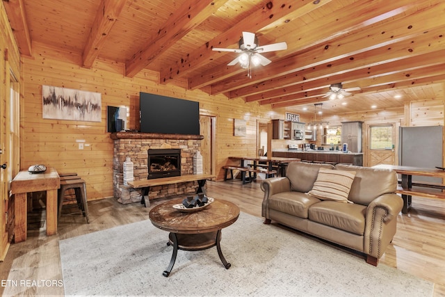 living room with beamed ceiling, light wood-type flooring, and wooden walls