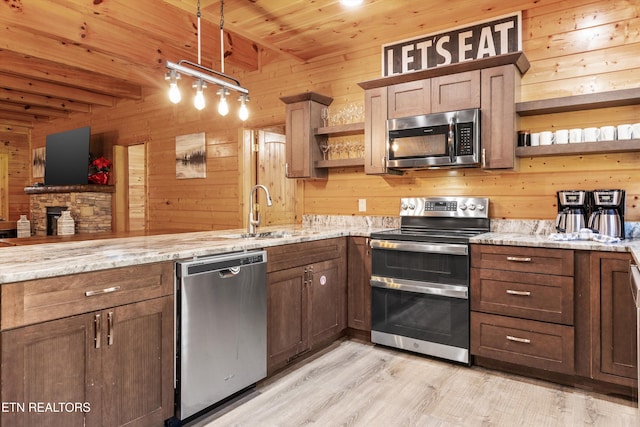 kitchen featuring light stone counters, stainless steel appliances, beam ceiling, light hardwood / wood-style floors, and wood walls