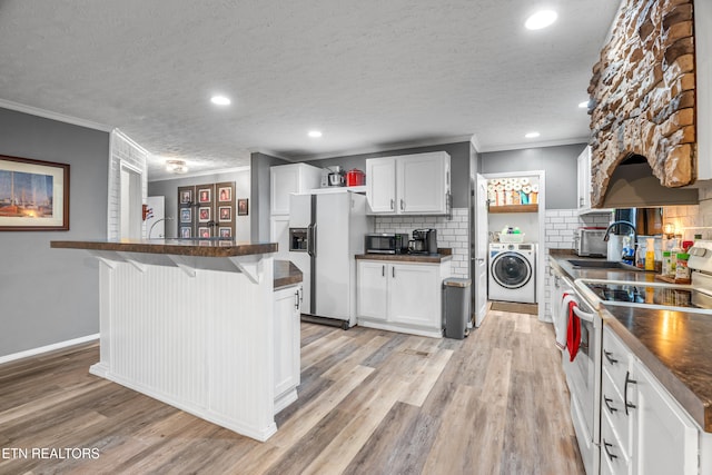 kitchen with a kitchen breakfast bar, stainless steel appliances, light hardwood / wood-style flooring, washer / dryer, and white cabinetry