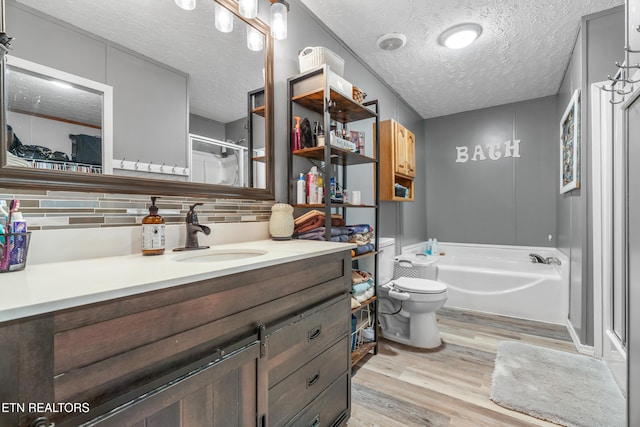 full bathroom with tasteful backsplash, vanity, a textured ceiling, hardwood / wood-style floors, and toilet