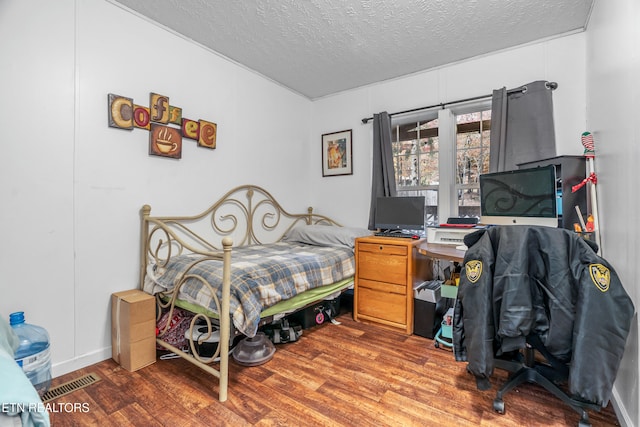 bedroom with a textured ceiling and hardwood / wood-style flooring