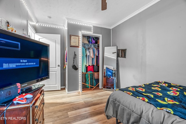 bedroom featuring crown molding, ceiling fan, light wood-type flooring, a textured ceiling, and a closet