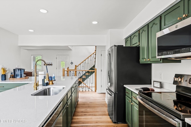 kitchen with sink, light wood-type flooring, green cabinetry, and appliances with stainless steel finishes