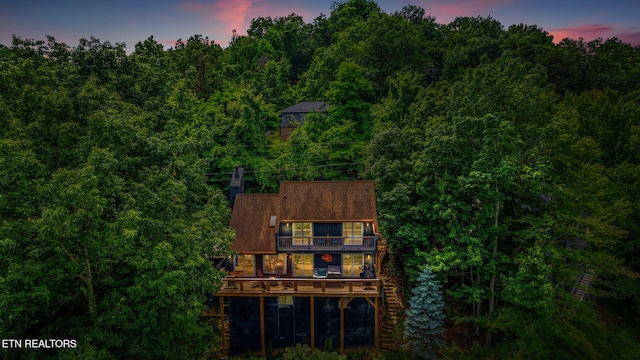 back house at dusk featuring a balcony