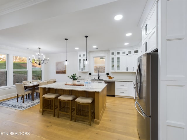 kitchen with stainless steel appliances, a sink, light wood-type flooring, a center island, and crown molding