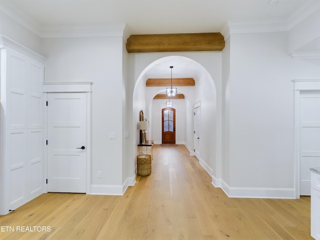 entrance foyer with crown molding, light wood finished floors, arched walkways, and baseboards