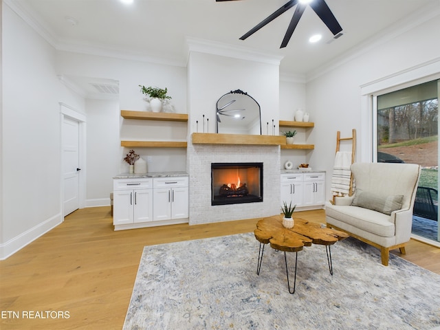 living room featuring light wood-style floors, a warm lit fireplace, ornamental molding, and baseboards