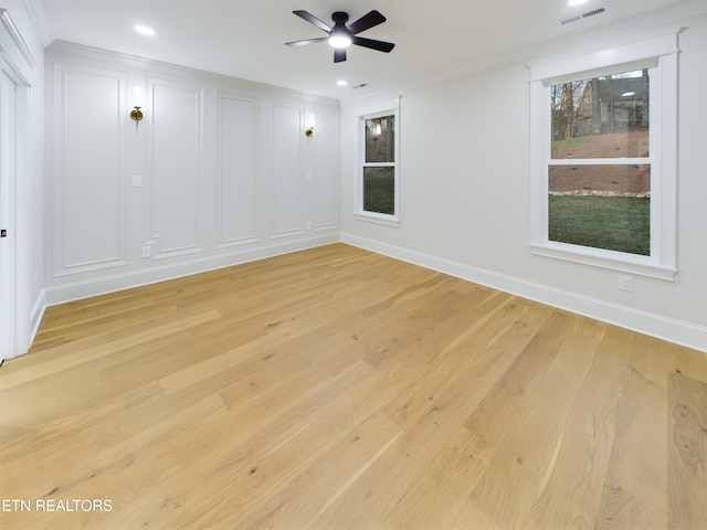 spare room featuring baseboards, visible vents, crown molding, and light wood finished floors