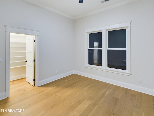 unfurnished room featuring a ceiling fan, light wood-style flooring, ornamental molding, and baseboards