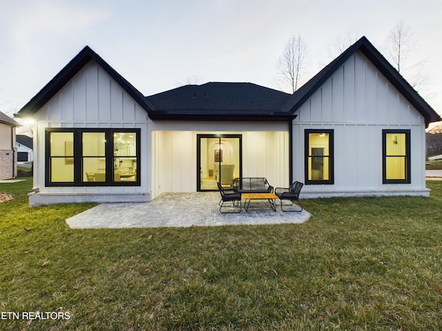 rear view of property with a yard, board and batten siding, and a patio area