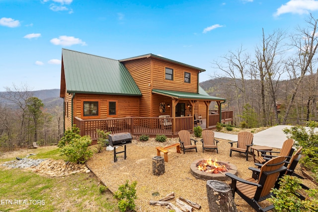 back of property with a wooden deck and a fire pit