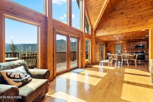 living room featuring a mountain view, wood ceiling, a towering ceiling, and light hardwood / wood-style flooring