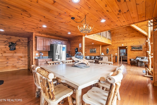 dining room featuring wooden walls, an inviting chandelier, wood ceiling, and light wood-type flooring