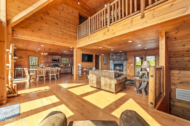 living room featuring light hardwood / wood-style floors, a stone fireplace, and wooden ceiling