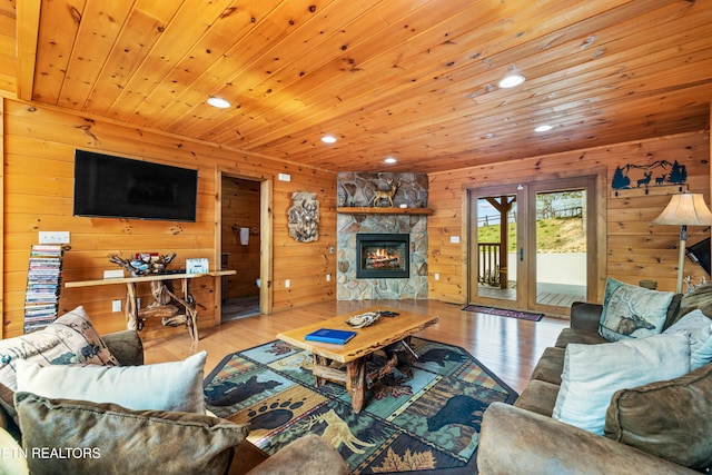 living room featuring a stone fireplace, light wood-type flooring, wooden walls, and wooden ceiling