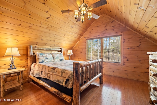 bedroom featuring hardwood / wood-style floors, lofted ceiling, wooden ceiling, wooden walls, and ceiling fan