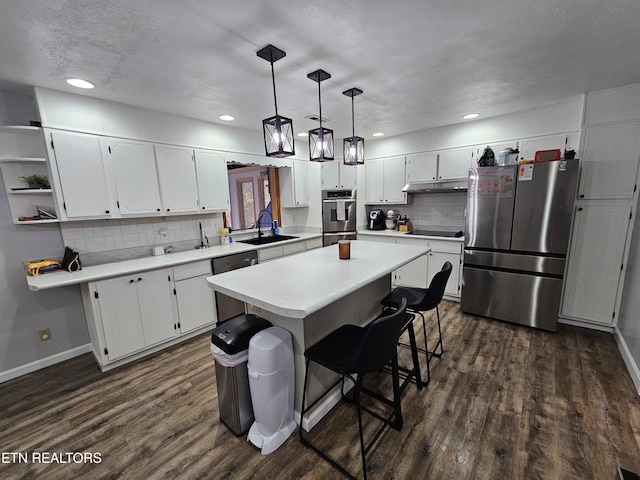 kitchen with white cabinetry, dark wood-type flooring, backsplash, decorative light fixtures, and appliances with stainless steel finishes