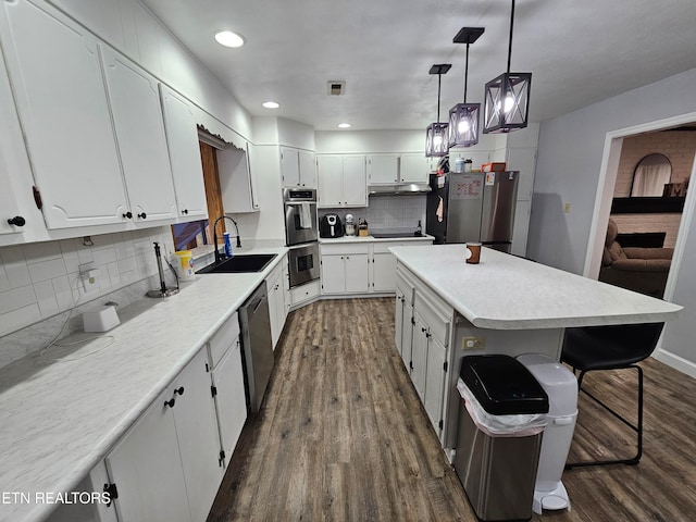 kitchen featuring a center island, sink, dark wood-type flooring, stainless steel appliances, and white cabinets