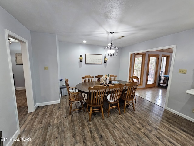 dining space with a textured ceiling, dark hardwood / wood-style flooring, and a notable chandelier