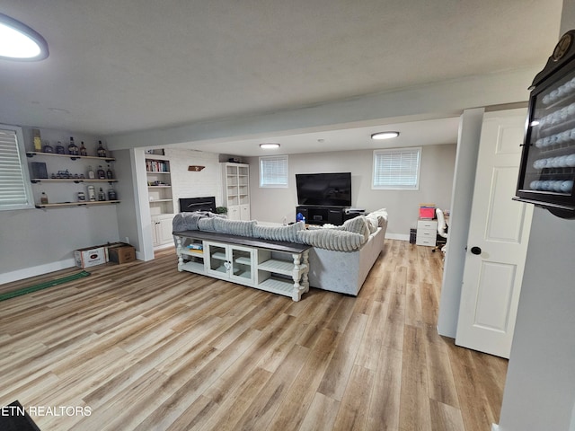 living room with built in shelves, a textured ceiling, and light wood-type flooring