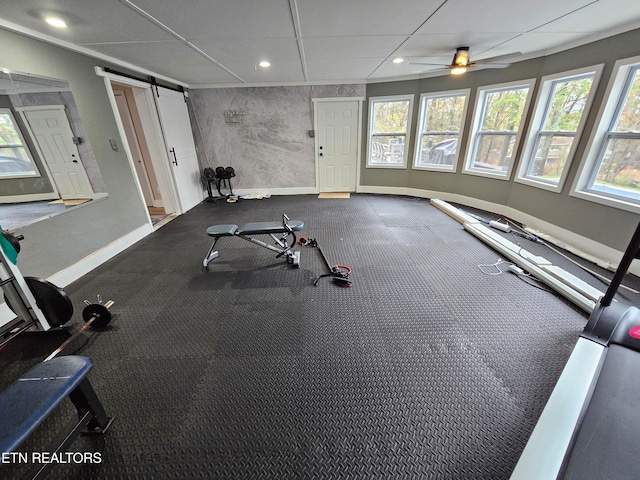 workout area with a barn door, ceiling fan, and a healthy amount of sunlight