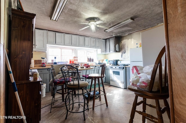 kitchen with a textured ceiling, white appliances, and ceiling fan